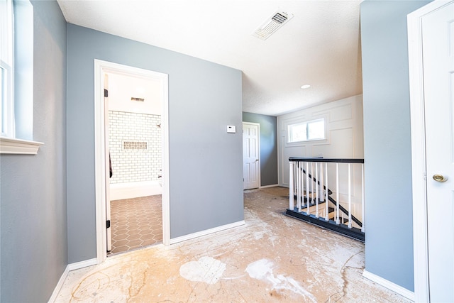 corridor with an upstairs landing, baseboards, and visible vents