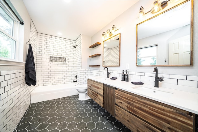 bathroom with toilet, a sink, double vanity, and tile walls