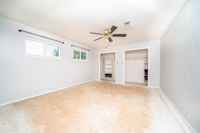 interior space with a textured ceiling, baseboards, ceiling fan, and visible vents