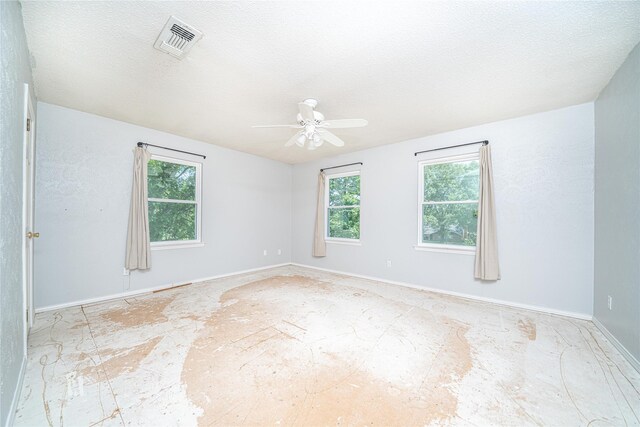 spare room with baseboards, a textured ceiling, ceiling fan, and visible vents