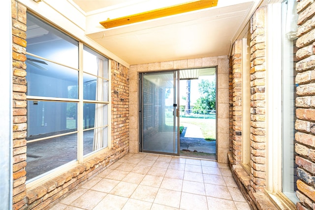 doorway featuring tile patterned floors and brick wall