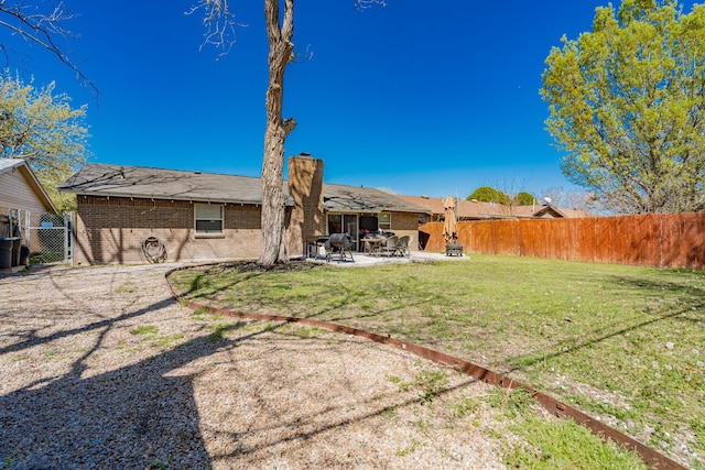 329 W Ferndale Ln, Grand Prairie, TX 75052 - back of property with a chimney, a fenced backyard, brick siding, a lawn, and a patio area