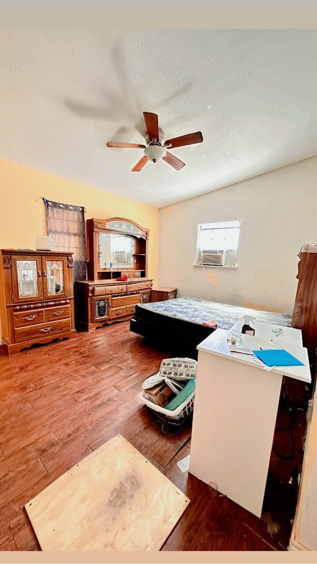 living area featuring a textured ceiling, wood finished floors, and a ceiling fan