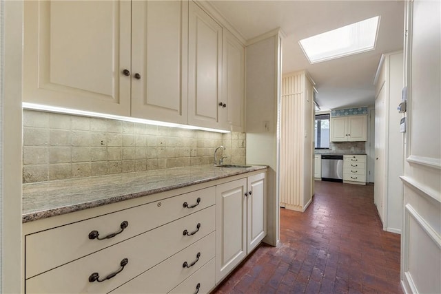 kitchen with a sink, a skylight, dishwasher, brick floor, and decorative backsplash