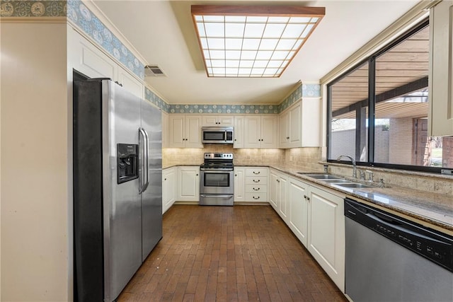 kitchen with a sink, stainless steel appliances, brick floor, and tasteful backsplash