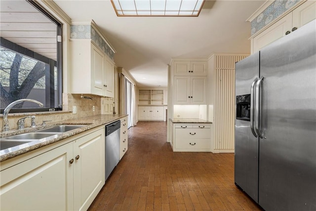kitchen featuring a sink, tasteful backsplash, appliances with stainless steel finishes, brick floor, and white cabinets