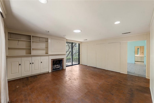 unfurnished living room with a fireplace, brick floor, visible vents, and recessed lighting