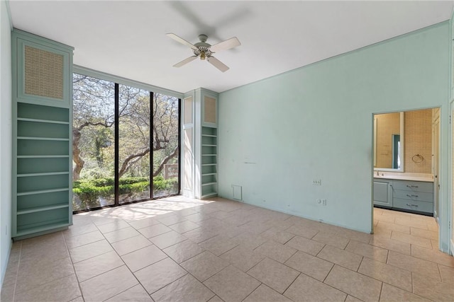 empty room with light tile patterned floors, a ceiling fan, and a wall of windows