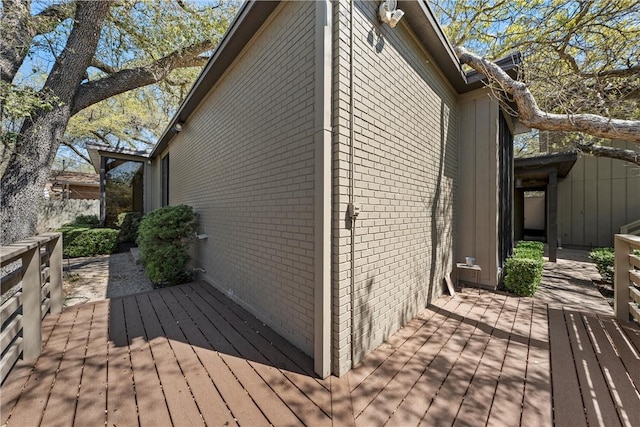 view of property exterior with brick siding and a wooden deck