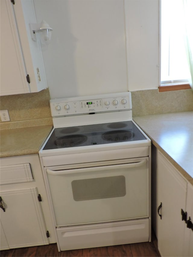 kitchen with dark wood-type flooring, white electric range oven, light countertops, and white cabinets