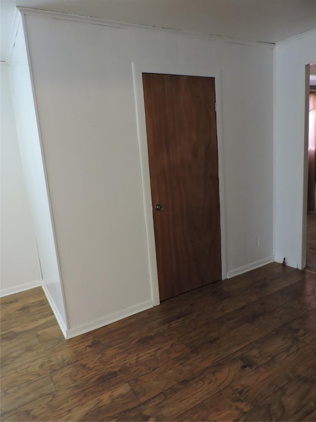 spare room with dark wood-type flooring and baseboards