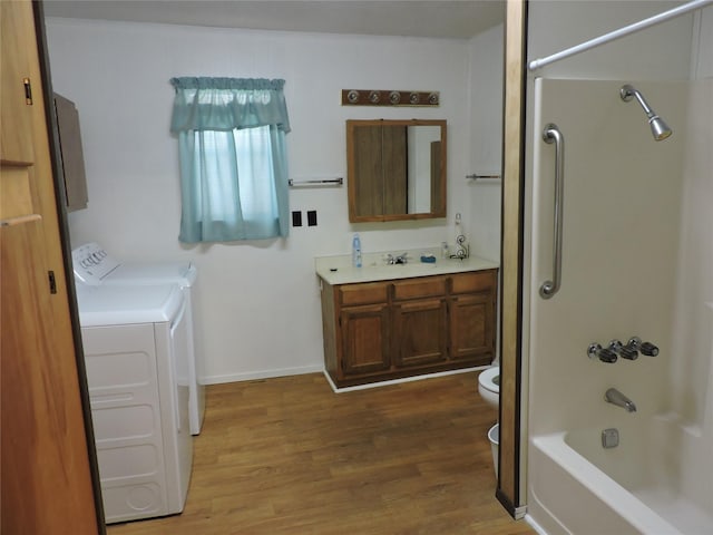 full bathroom featuring independent washer and dryer, bathing tub / shower combination, vanity, toilet, and wood finished floors