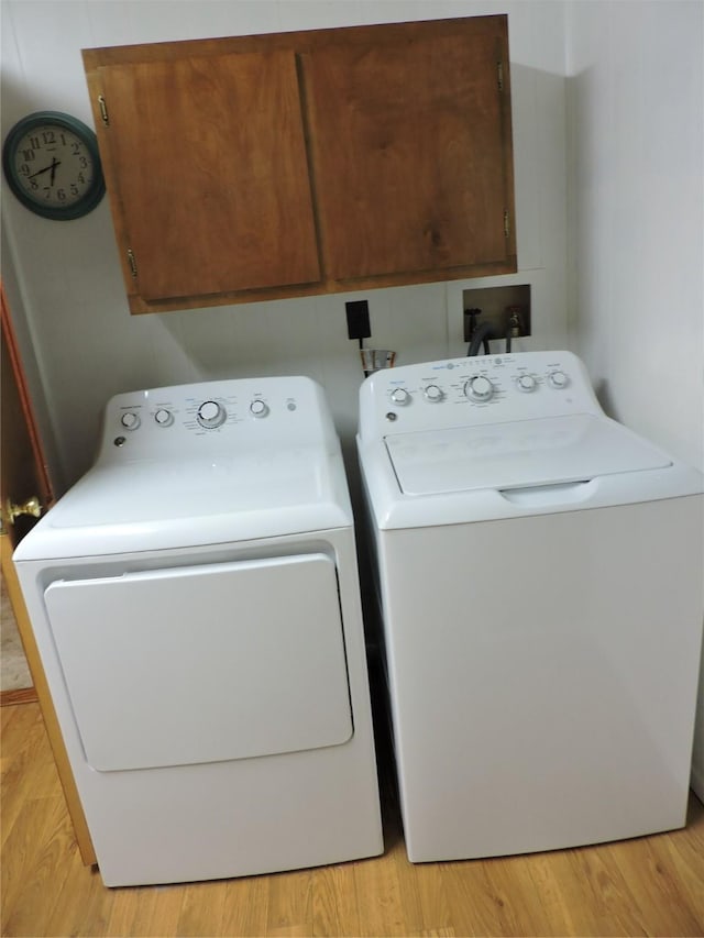 laundry area featuring light wood-style floors, cabinet space, and washer and clothes dryer