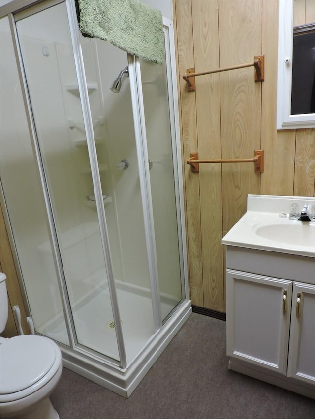 bathroom featuring toilet, vanity, and a shower stall