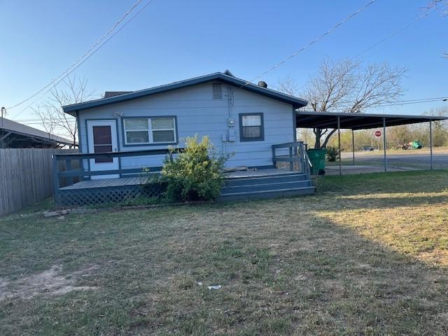 exterior space with an attached carport, a yard, a wooden deck, and fence