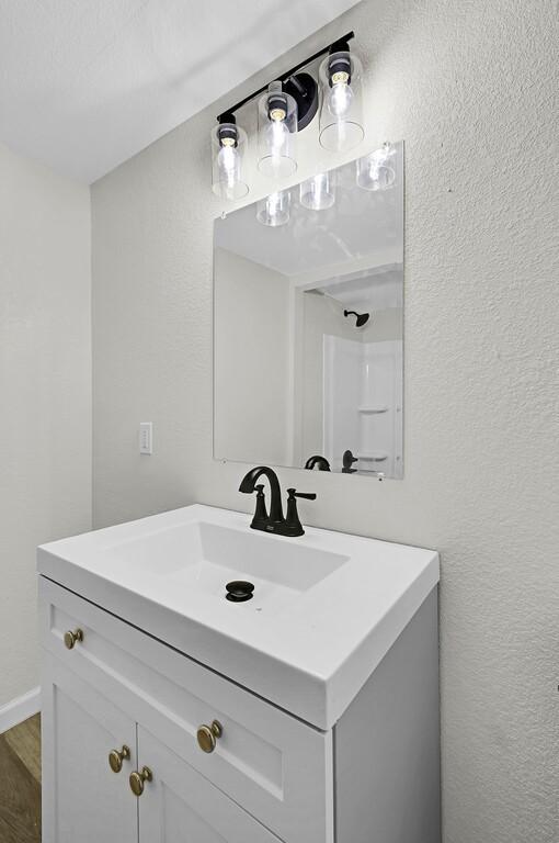 1541 Clark Ave, Waco, TX 76708 - bathroom featuring wood finished floors, a textured wall, and vanity