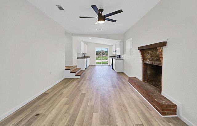 1541 Clark Ave, Waco, TX 76708 - unfurnished living room featuring light wood-style flooring, a sink, ceiling fan, a brick fireplace, and visible vents