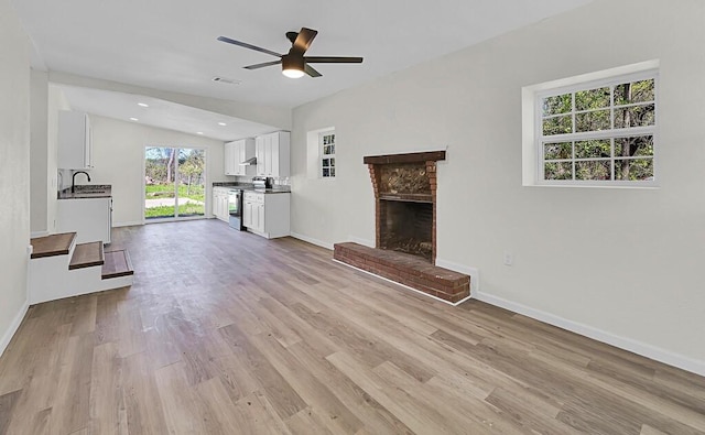 1541 Clark Ave, Waco, TX 76708 - unfurnished living room with a brick fireplace, light wood finished floors, baseboards, ceiling fan, and lofted ceiling