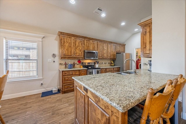 4711 Bering Dr, Sanger, TX 76266 - kitchen featuring appliances with stainless steel finishes, a peninsula, brown cabinets, baseboards, and light wood-style flooring