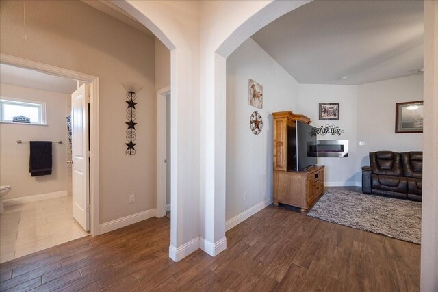 4711 Bering Dr, Sanger, TX 76266 - hallway with arched walkways, dark wood-style flooring, vaulted ceiling, and baseboards