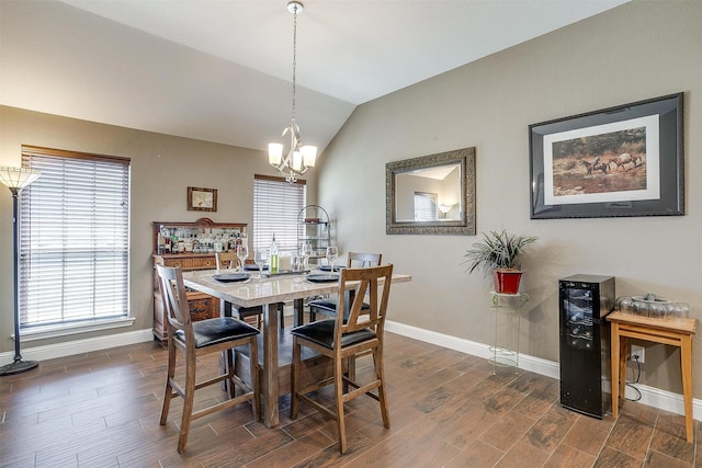 dining room with a wealth of natural light, a notable chandelier, vaulted ceiling, and wood finished floors