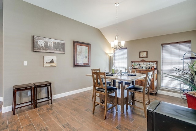 dining room featuring dark wood-type flooring, baseboards, vaulted ceiling, and a chandelier