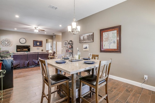 dining room with ceiling fan with notable chandelier, dark wood finished floors, baseboards, visible vents, and recessed lighting