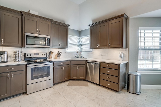 kitchen with backsplash, light countertops, a sink, and stainless steel appliances