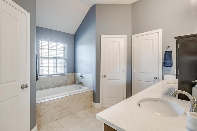 bathroom with a bath, lofted ceiling, a sink, and double vanity