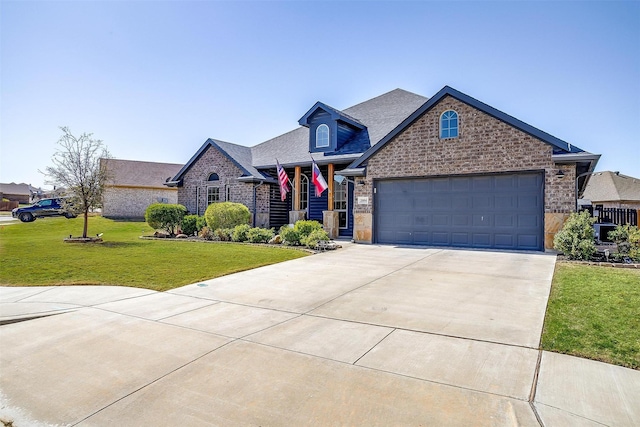 view of front facade featuring roof with shingles, driveway, a front lawn, brick siding, and a garage