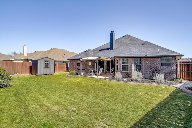 rear view of house featuring a chimney, a fenced backyard, an outdoor structure, and a patio area
