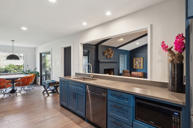 kitchen featuring a sink, blue cabinets, a brick fireplace, stainless steel appliances, and light wood-style floors