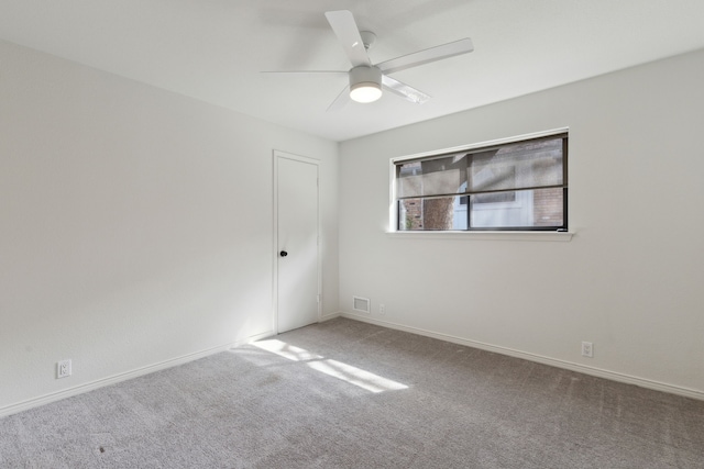 carpeted empty room with baseboards, visible vents, and ceiling fan