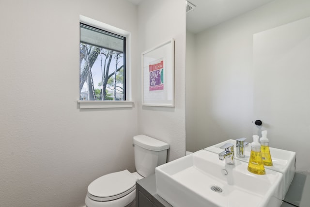 bathroom featuring toilet, a sink, and visible vents
