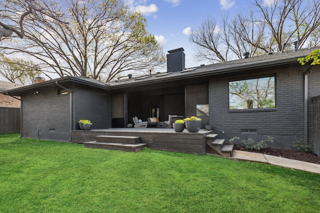 back of house with a lawn, brick siding, and a chimney