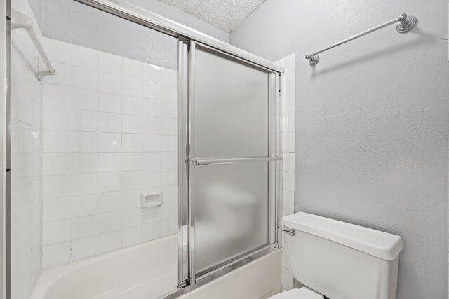 5300 Keller Springs Rd Unit 2044, Dallas, TX 75248 - full bath featuring a textured wall, toilet, a textured ceiling, and enclosed tub / shower combo