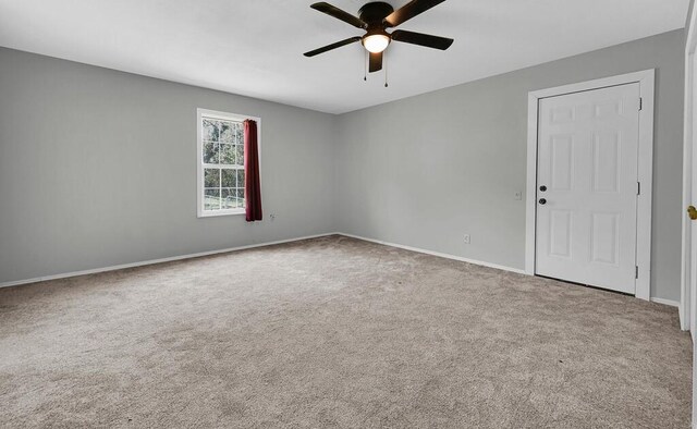 carpeted spare room featuring baseboards and ceiling fan