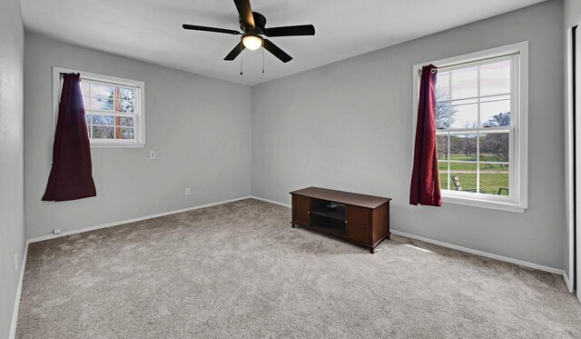 spare room featuring a ceiling fan, baseboards, and light colored carpet