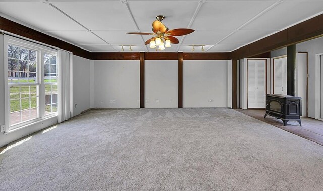 spare room with ceiling fan, carpet floors, a wood stove, and visible vents
