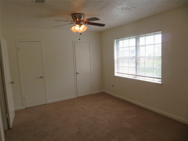empty room featuring light colored carpet, ceiling fan, and baseboards