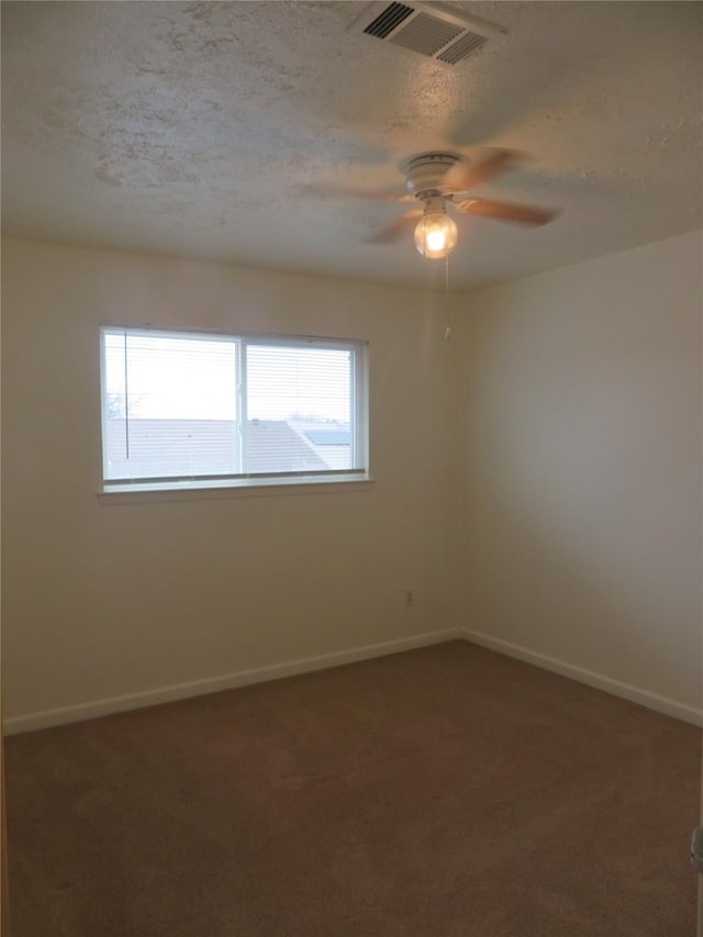 carpeted spare room featuring ceiling fan, baseboards, visible vents, and a wealth of natural light
