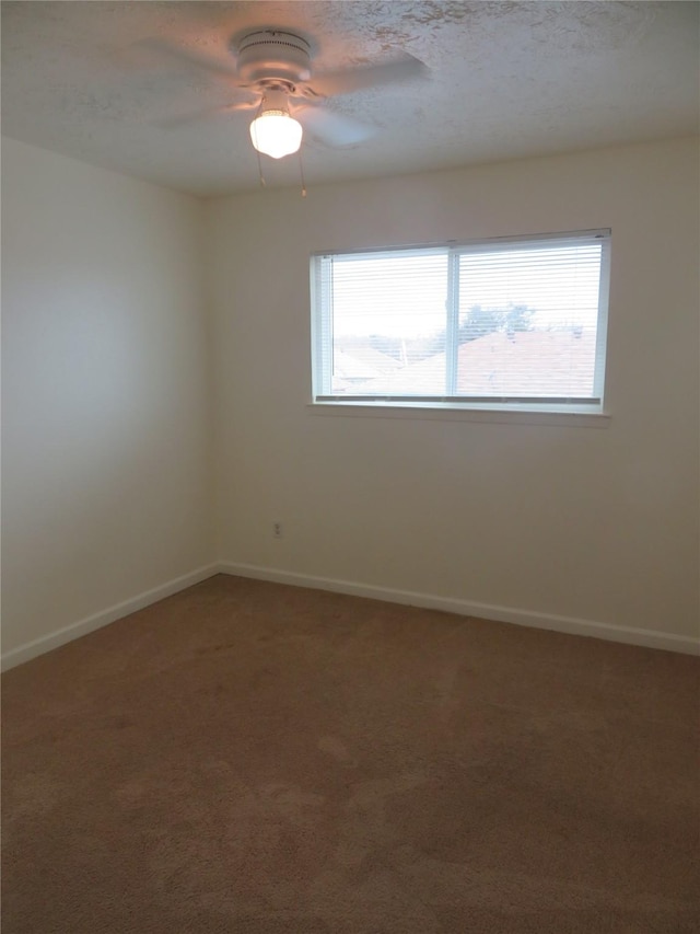 carpeted spare room featuring a wealth of natural light, ceiling fan, and baseboards