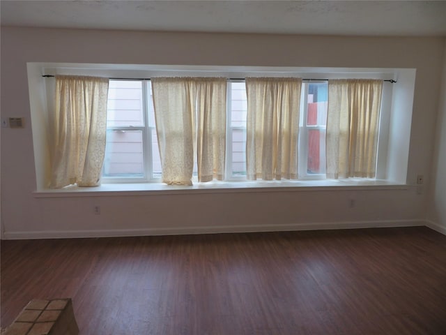 unfurnished room with dark wood-style flooring and baseboards