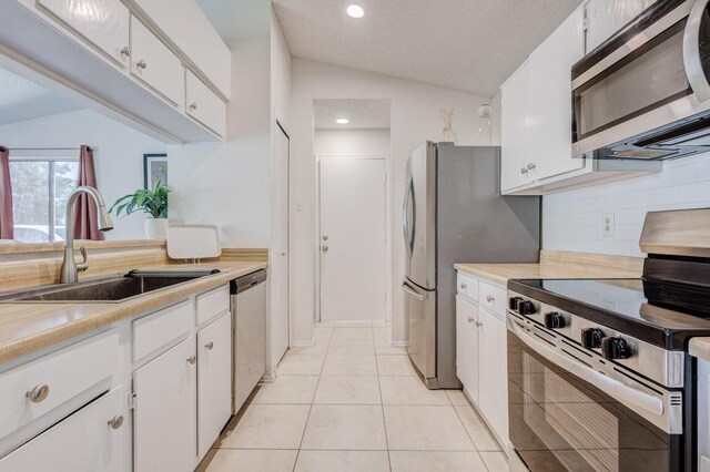 1201 High Valley Dr, Garland, TX 75041 - kitchen with appliances with stainless steel finishes, light countertops, a sink, lofted ceiling, and decorative backsplash