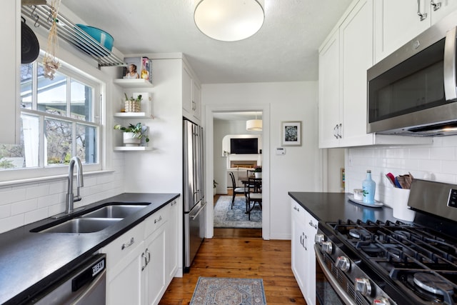 6926 Santa Monica Dr, Dallas, TX 75223 - kitchen featuring a sink, white cabinetry, stainless steel appliances, dark countertops, and dark wood-type flooring
