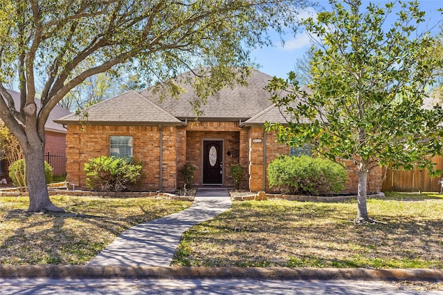 single story home featuring a shingled roof, fence, and brick siding