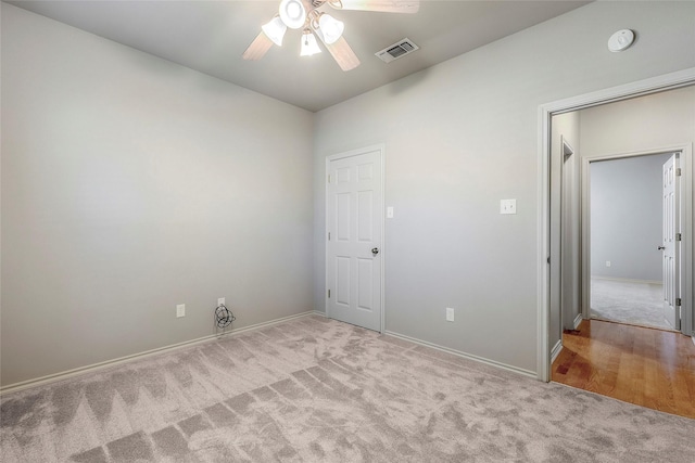 carpeted spare room featuring baseboards, visible vents, and ceiling fan