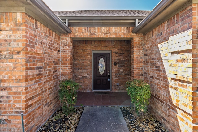 entrance to property with brick siding and roof with shingles