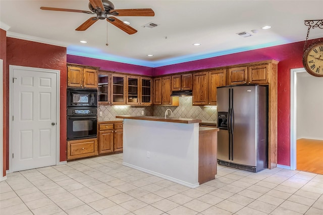 kitchen with visible vents, brown cabinets, tasteful backsplash, under cabinet range hood, and black appliances