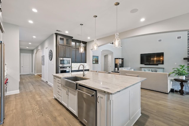 3905 Dashiell Dr, Flower Mound, TX 75022 - kitchen with arched walkways, stainless steel appliances, a sink, light wood-style flooring, and recessed lighting